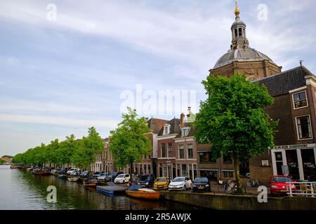 Leiden, Niederlande, 09. Mai 2022. Der von Bäumen gesäumte Kanal Oude Vest, traditionelle Häuser und die protestantische Kirche Marekerk. Stockfoto