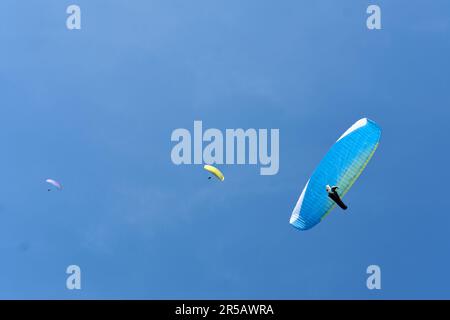 Gleitschirmfliegen, eine Gruppe von Gleitschirmfliegen am klaren blauen Himmel. Ansicht aus niedrigem Winkel. Stockfoto