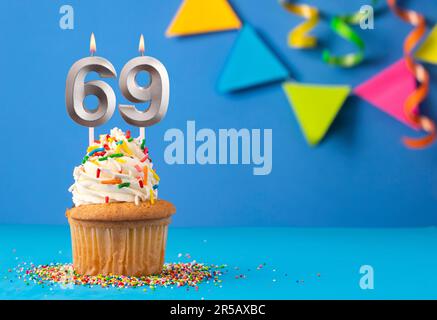 Geburtstagskuchen mit Kerze Nummer 69 - blauer Hintergrund Stockfoto