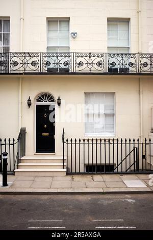 Belgravia, London, Großbritannien. 27. April 2022 Reihenhaus mit Stuckfassade, schwarzer Vordertür und Geländern. Stockfoto