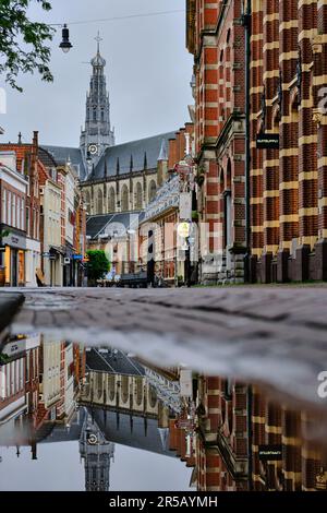 Haarlem, Holland, 23. Mai 2022: Blick aus dem niedrigen Winkel auf eine leere Einkaufsstraße Zijlstraat in Haarlem. Die Grote Kerk Kirche im Hintergrund. Reflexionen in Stockfoto