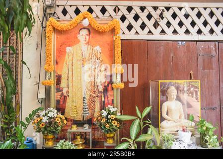 Bangkok, Thailand - 1. Mai 2023: Ein Porträt von König Rama IX. Und eine Buddha-Statue in einer Gasse von Chinatown. Stockfoto