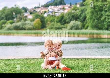 Außenporträt von bezaubernden, glücklichen Kindern, die zusammen am See oder Fluss spielen, Geschwister lieben Stockfoto