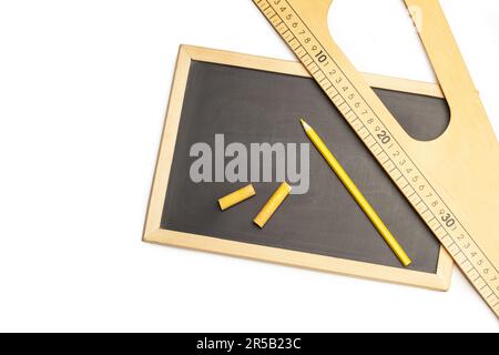 Dreieckiges Holzlineal, gelber Bleistift und Kreide auf einer Tafel und auf weißem Hintergrund mit Kopierbereich Stockfoto