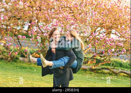 Außenporträt eines glücklichen romantischen Paares, Frau, die auf dem Rücken ihres Freundes sitzt, glückliche Beziehungen Stockfoto