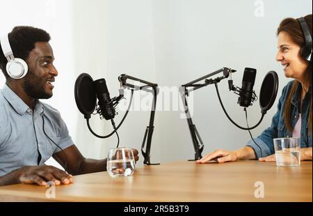 Fröhliche Multirassenfreunde nehmen einen Podcast auf – Mann und Frau haben Spaß bei der Zusammenarbeit Stockfoto