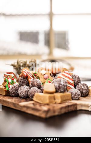 Eine festliche Weihnachtsszene mit einem Holztisch mit einem Tablett mit frisch gebackenen Zuckerkeksen in der Nähe eines Fensters mit Weihnachtsdekorationen Stockfoto