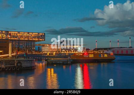 Kopenhagen, Dänemark - 13. September 2010: Spätabendlicher Blick über den Hafen mit königlichem Theater in der Ecke, Fähre auf dem Hafenwasser und Opernhaus in B Stockfoto