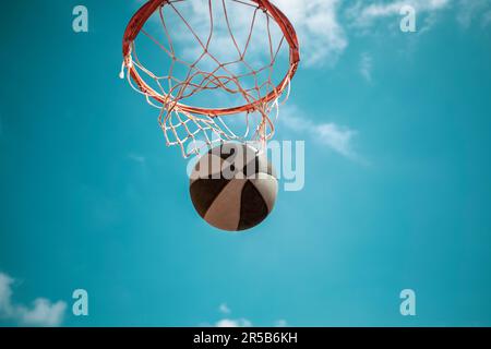 Basketballkorb von unten gesehen mit blauem Himmel und einem Taucherball Stockfoto