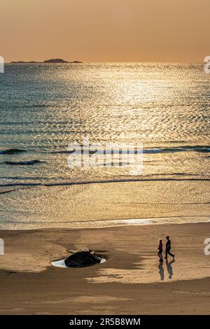 Junge Paare gehen bei Sonnenuntergang am Strand von Whitesands Bay, einem Strand mit der Blauen Flagge, der Halbinsel St. David, dem Nationalpark Pembrokeshire Coast, West Wales Stockfoto