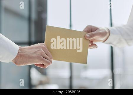 Zugeschnittenes Foto eines stilvollen Mannes, der einen versiegelten Papierumschlag übergibt Stockfoto