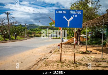 Ein blaues Straßenschild auf der Straße QL40, das auf die Grenze zu Kambodscha und Laos in der Gemeinde Bo Y, Bezirk Ngoc Hoi, im zentralen Hochland in Vietnam zeigt. Die s Stockfoto