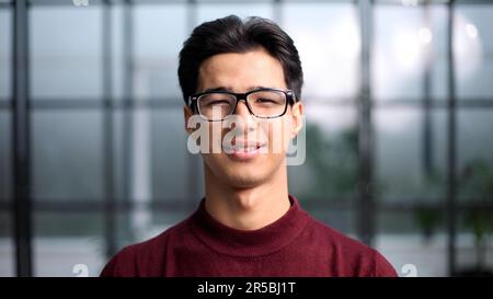 Ein hübscher junger asiatischer Mann, der in einem roten Pullover lächelt und in die Kamera lächelt Stockfoto