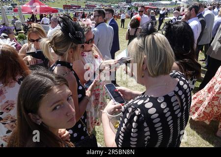 Epsom, Surrey, Großbritannien. 2. Juni 2023. Szenen in den Betfred Oaks, während des Betfred Derby Festivals - hier: Stilvolle Rennfahrer vergleichen Wetten auf ihre iPhones in der Sonne vor dem Hauptrennen des Tages. Credit: Motofoto/Alamy Live News Stockfoto