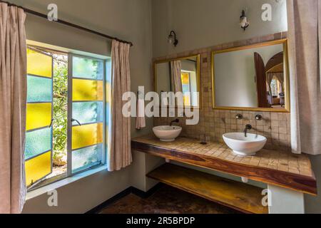 Ein modernes Badezimmer gehört zu jeder Suite im Huntingdon House auf dem Satemwa-Anwesen in der Nähe von Thyolo, Malawi. Das um 1935 erbaute Herrenhaus bietet nur fünf Gästezimmer, die im Kolonialstil eingerichtet sind, und ist das ehemalige Zuhause der Familie, die noch immer die Satemwa-Tee- und Kaffeeplantage besitzt. Stockfoto