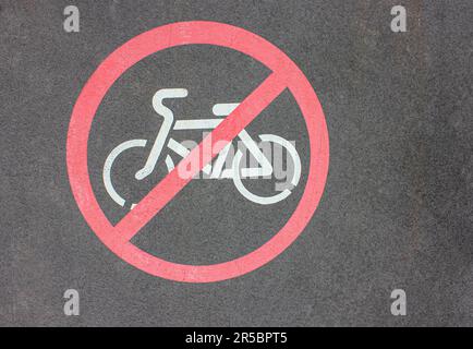 Straßenabschnitt mit Markierungen, die die Bewegung von Radfahrern regulieren. Keine Radtouren Erlaubt. Rundes rotes Verkehrsschild. Weißes Fahrrad-Symbol, über Grau Gemalt A Stockfoto