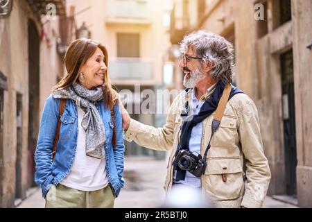 Lächelndes älteres Paar, das sich unterhält und in der Stadt spazieren geht. Reife Eheschließung Stockfoto
