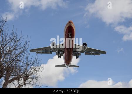 Schöner Hintergrund mit einem fliegenden Flugzeug am Himmel.Flugzeug mit Fahrwerk am Himmel ausgefahren.Reisekonzept mit Kopierraum Stockfoto