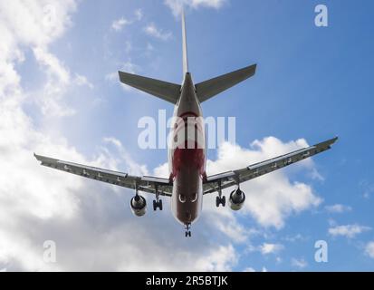 Passagierflugzeug mit ausgefahrenem Fahrwerk am Himmel. Reisekonzept mit Kopierraum Stockfoto