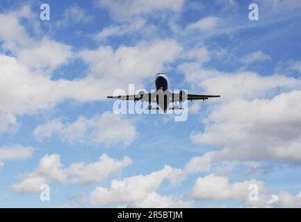 Wunderschöner Hintergrund mit einem fliegenden Flugzeug am blauen Himmel. Passagierflugzeug mit ausgefahrenem Fahrwerk am Himmel. Reisekonzept mit Kopierraum Stockfoto