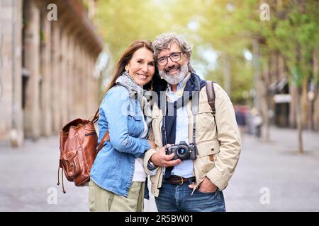 Porträt eines glücklichen älteren Touristenpaares, das sich für ein Foto im Freien in der Stadt posiert. Lächelnde Senioren. Stockfoto