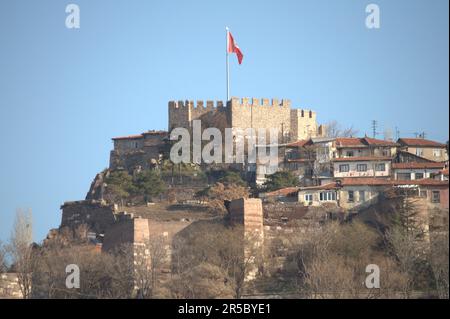 Ein Blick aus der Vogelperspektive auf ein majestätisches Schloss hoch oben auf einem malerischen Hügel, dessen rote Flagge im Wind flattert Stockfoto