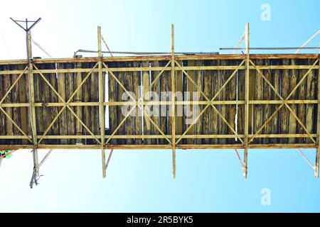 Stahl- und Holzbrücke für Fußgänger mit blauem Himmel im Hintergrund. Bottom-up-Ansicht Stockfoto