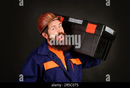 Handwerker mit Werkzeugkasten. Baumeister in Uniform mit Instrumentenbox. Reparaturwerkzeuge. Handwerker, Handwerker mit Schutzhelm und Reparatursatz. Handwerker Stockfoto