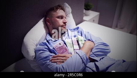 Mann schlafend auf dem Bett mit Bündel von Banknoten Stockfoto