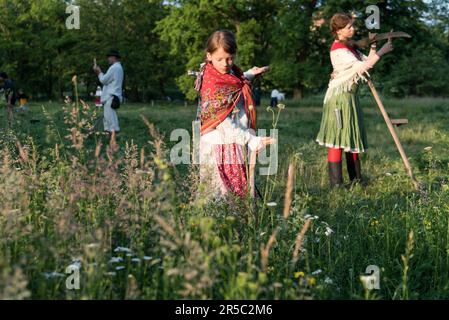 Prag, Tschechische Republik. 02. Juni 2023. Ein Mädchen in traditioneller Arbeitskleidung benutzt eine Sense, um die Wiese zu Fällen. Rund 50 Einheimische kommen zusammen, um Blumenwiesen im Stromovka Park zu mähen, dem größten Park in Prag, der sich in der Nähe des historischen Stadtzentrums befindet. (Foto: Tomas Tkacik/SOPA Images/Sipa USA) Guthaben: SIPA USA/Alamy Live News Stockfoto