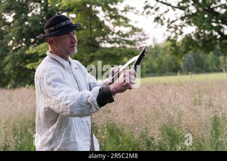 Prag, Tschechische Republik. 02. Juni 2023. Ein Mann in traditioneller Arbeitskleidung schärft die Sense bei Sonnenaufgang. Rund 50 Einheimische kommen zusammen, um Blumenwiesen im Stromovka Park zu mähen, dem größten Park in Prag, der sich in der Nähe des historischen Stadtzentrums befindet. (Foto: Tomas Tkacik/SOPA Images/Sipa USA) Guthaben: SIPA USA/Alamy Live News Stockfoto