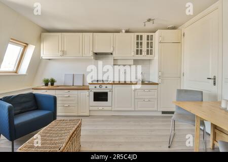 Eine Küche und Essbereich in einem winzigen Haus mit weißen Schränken, Holzboden und blauen Sofas auf der rechten Seite Stockfoto