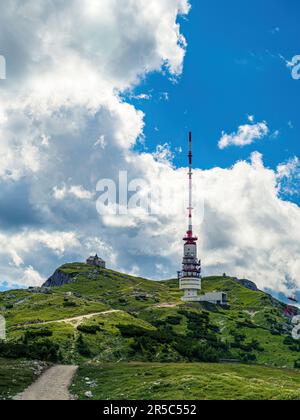 Fernsehradioturm und Kapelle auf dem Gipfel des Dobratsch in Kärnten, Österreich, Sommer, bewölkter dramatischer Himmel, Wildblumen alpine Landschaft Stockfoto