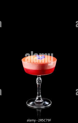 Sommer-erdbeercocktail mit violetter Blume isoliert auf schwarzem Hintergrund. Frischer alkoholischer Cocktail. Stockfoto