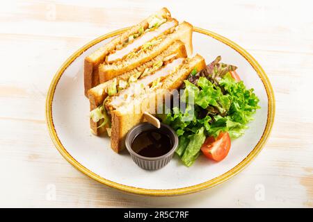 Knuspriges Sandwich mit gebratenem Hähnchen und Grün auf weißem Holzhintergrund. Stockfoto