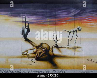 Eine städtische Straßenszene mit einem Graffiti-Wandgemälde, auf dem ein Mann vor einer Frau wegläuft Stockfoto