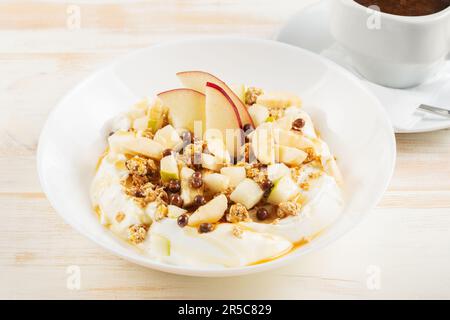 Gesundes Βreakfast-Konzept. Joghurt mit Flocken, Obst und Honig auf Holzhintergrund. Stockfoto