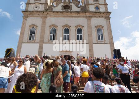 Eine Gruppe von Menschen ist um die Stufen einer großen Steinkirche versammelt, mit einem majestätischen Turm im Hintergrund Stockfoto