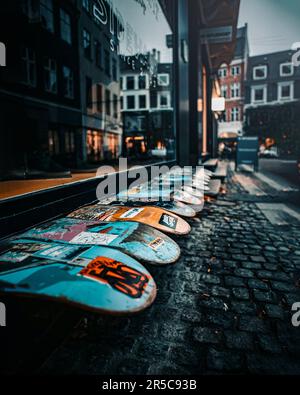 Eine Reihe von Skateboards stand auf dem Bürgersteig neben dem Glasfenster in der Stadt Stockfoto