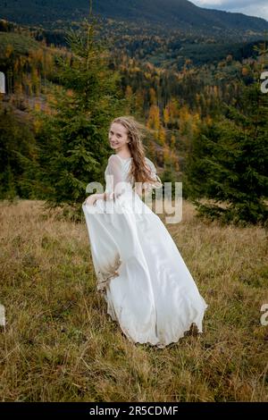 Die Braut rennt den Hügel hinunter und hebt das herrliche Kleid. Stockfoto