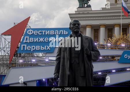 Moskau, Russland. 2. Juni 2023. Denkmal für den sowjetischen Führer Wladimir Lenin vor dem Hintergrund des Emblems des Allrussischen Festivals der Kinder- und Jugendbewegung der Ersten in WDNKh Stockfoto