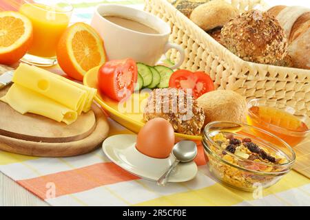 Frühstück mit Brötchen, Ei, Käse, Kaffee und Orangensaft auf dem Tisch Stockfoto