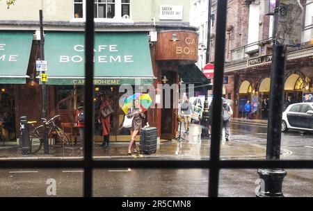 Eine Frau schützt vor dem Regen unter einem Regenbogenschirm an der Ecke von Greek Street und Old Compton Street in Soho, London. 8. September 2022 Stockfoto