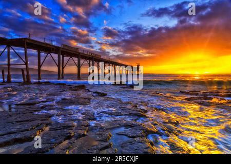 Malerischer, farbenfroher Sonnenaufgang über dem Pazifik am Middle Camp Beach in der Catherine Hill Bay in der Nähe des historischen Stegs. Stockfoto