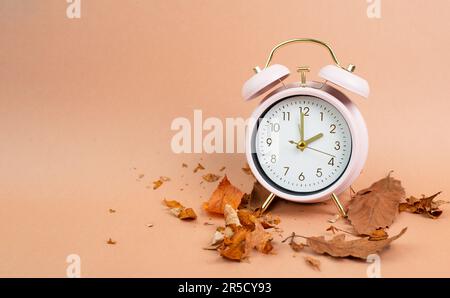 Wecker mit Herbstlaub, Ende der Sommerzeit im Herbst, Umstellung auf Winterzeit Stockfoto