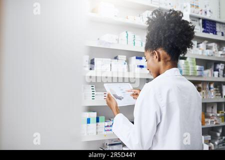 Sie sollten diese Bestandsverwaltungssoftware ausprobieren. Ein Apotheker, der eine digitale Tablette in einer Apotheke benutzt. Stockfoto