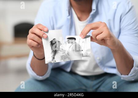 Scheidung und Trennung. Ein Mann rickte zu Hause ein Foto, Nahaufnahme. Ein Schwarzweißbild symbolisiert den Verlust von Gefühlen Stockfoto