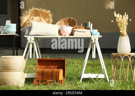 Viele verschiedene Gegenstände auf dem weißen Tisch im Hof. Garagenverkauf Stockfoto