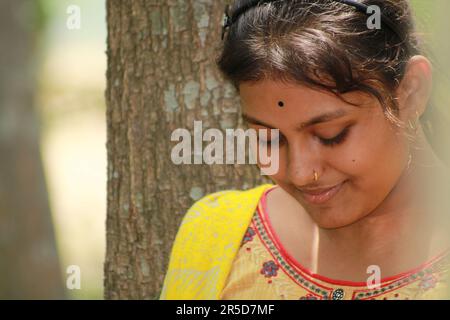 Nahaufnahme eines indischen Teenagers, das über den Naturhintergrund in die Kamera schaut. Stockfoto