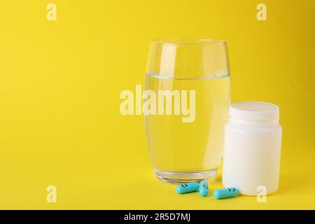 Antidepressiva mit fröhlichen Emoticons, medizinisches Glas und Glas Wasser auf gelbem Hintergrund, Platz für Text Stockfoto